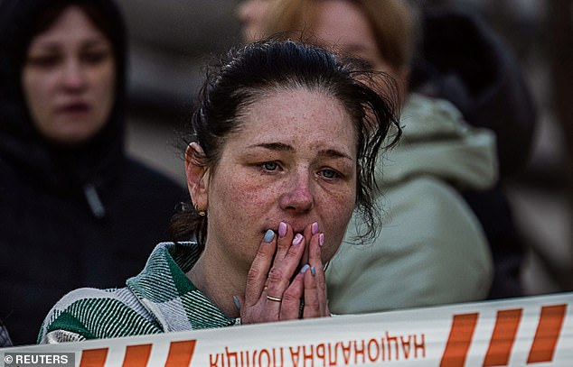 A local resident witnesses her neighbours in body bags on the ground after they were killed in a Russian missile strike in Uman