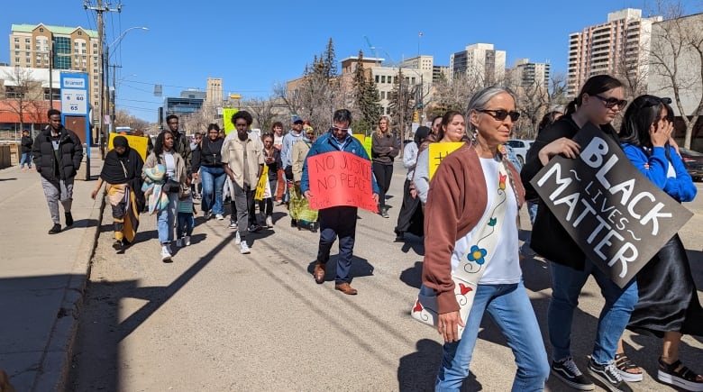 People walking down street holding signs