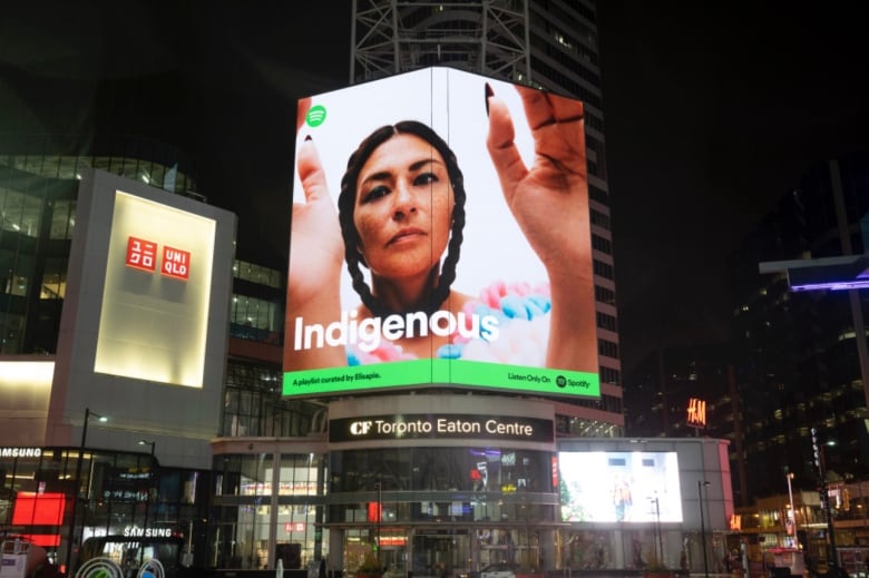 Woman on poses billboard at busy intersection in downtown Toronto.