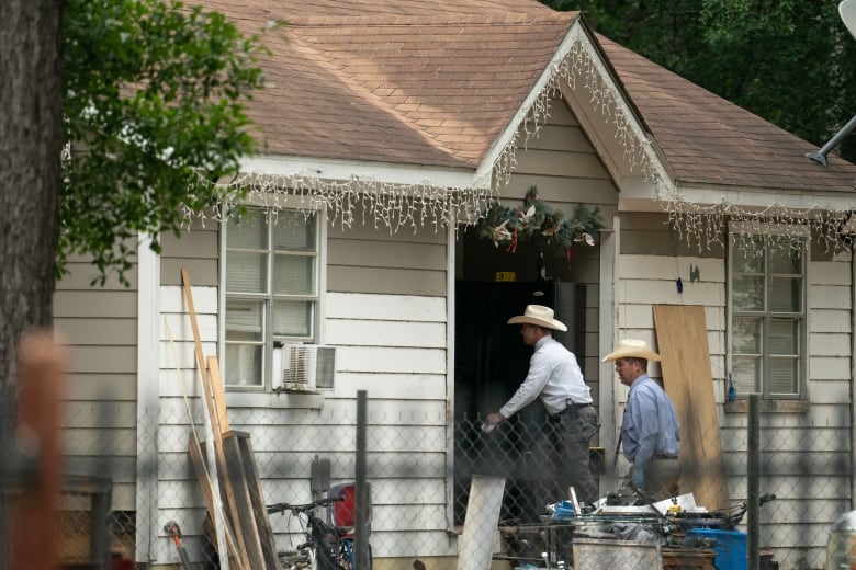 People wearing cowboy hats enter a house through the front door.