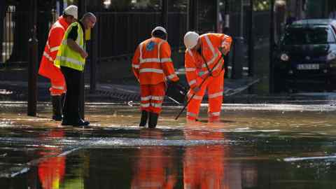 Workers in high visibility jackets clear flooded streets