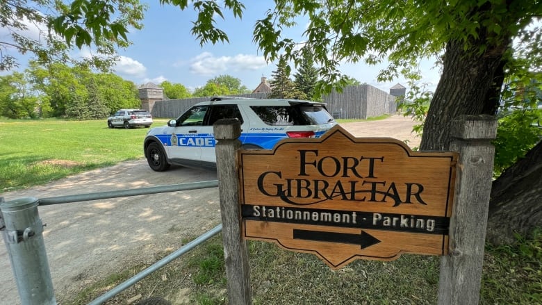 Two police vehicles are pictured behind a fence and sign which reads 'Fort Gibraltar.'