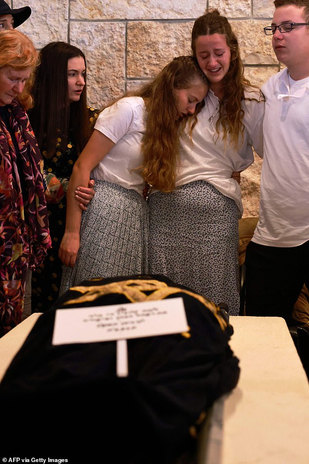 The three surviving children of  Lucy Dee, mourn by her body during her funeral at the Kfar Etzion settlement cemetery in the occupied West Bank, on April 11, 2023