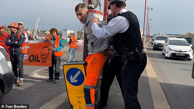 Police grapple with the commuter who was seen trying to remove Just Stop Oil activists from the road