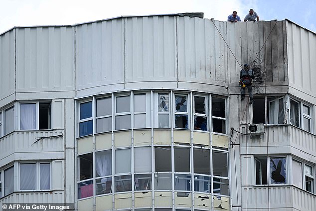 A specialist inspects the damaged facade of a multi-storey apartment building after a reported drone attack in Moscow on Tuesday