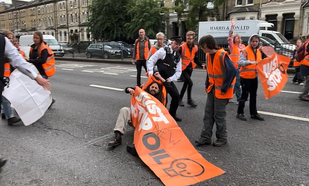 A policeman drags a Just Stop Oil activist after they stop traffic on Gloucester Road