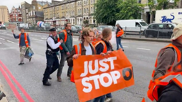 A police officer pushes protesters out of the middle of the road