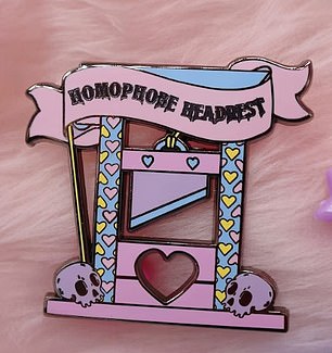 A guillotine pin with the words 'homophobe headrest' and pair of axes calling for the 'fight for trans rights' are also for sale online