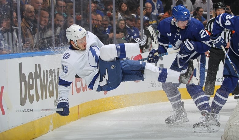 A hockey player is checked into the boards.