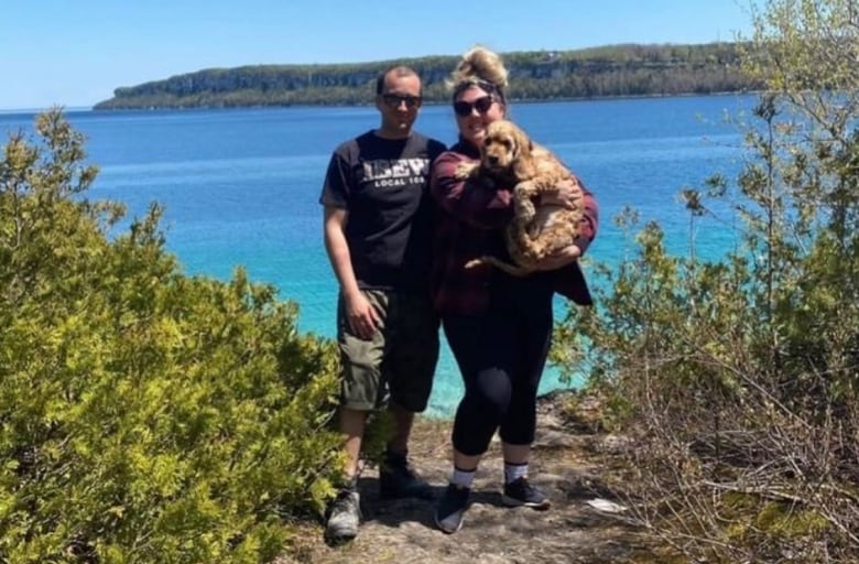 Two people standing holding a dog.