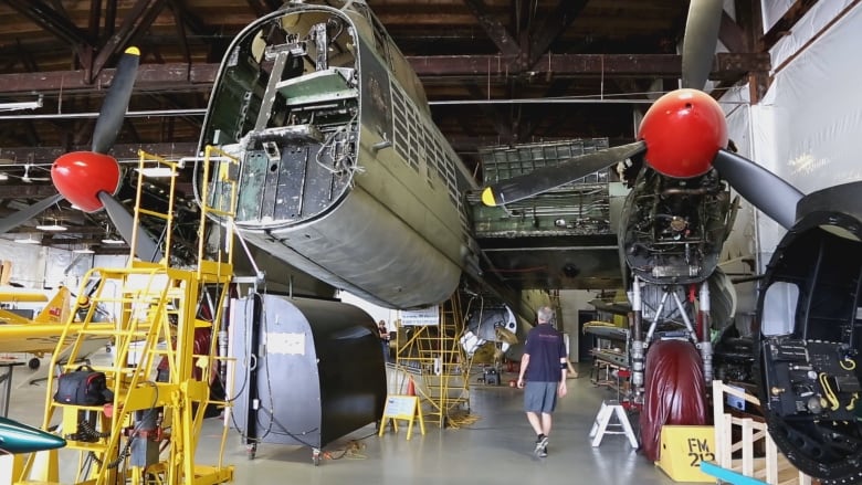 A Second World War Lancaster Bomber plane being restored in an airplane hangar. 