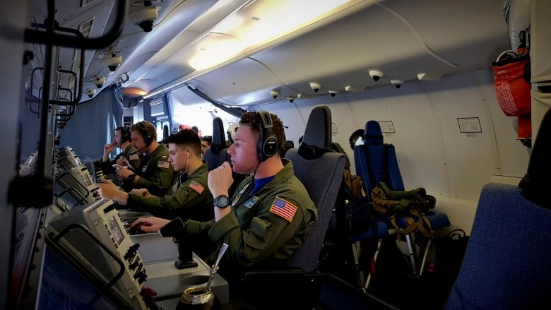 US Navy personnel look at screens aboard the U.S. Navy P-8A Poseidon aircraft while searching for Argentina's ARA San Juan submarine in the Southern Atlantic, Sunday, Nov. 26, 2017.