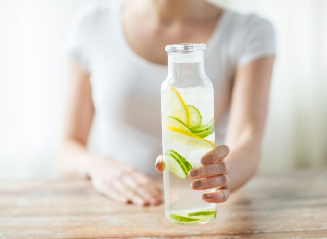 woman holding lemon cucumber water