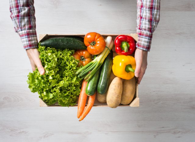 man holding crate of fresh garden vegetables