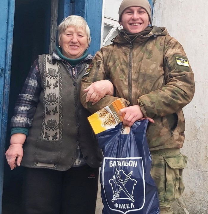 Unknown member of the Fakel battalion and a woman holding a plastic bag with Fakel iogo on it