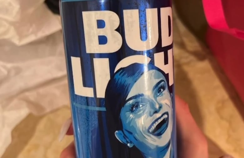 A beer can with a woman's face printed on the can is held up to the camera.