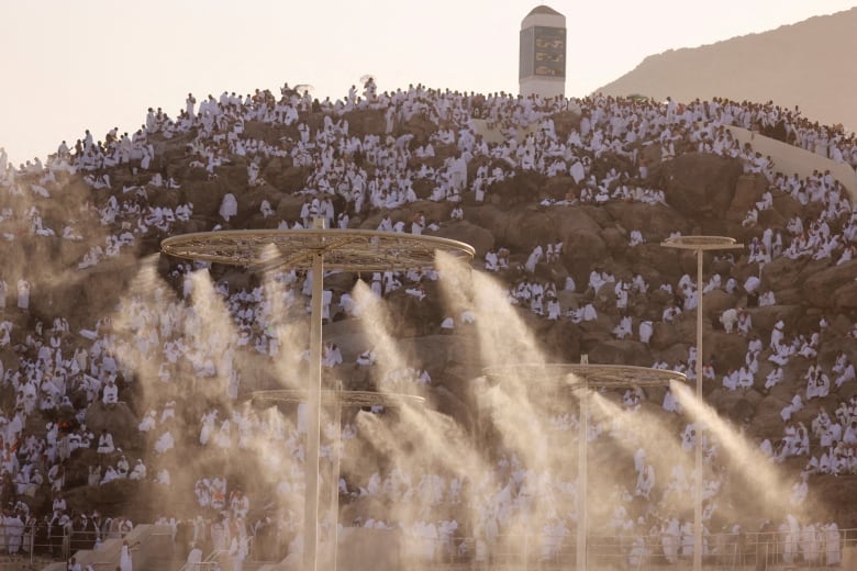 People are pictured on top of a mountain while water sprays to cool them off during hot temperatures.