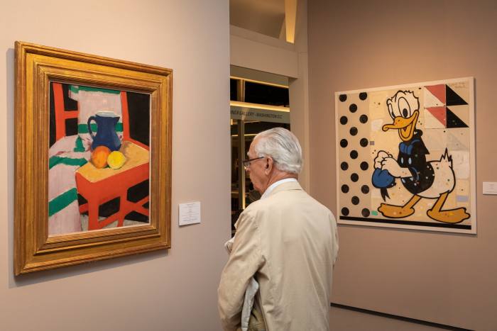 A visitor gazes at a painting hung on the wall at an art fair 