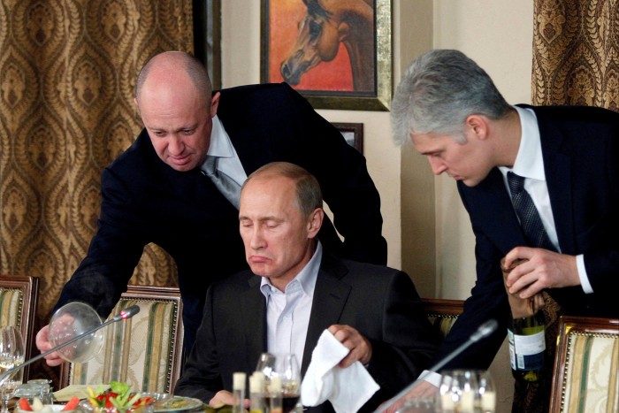 Yevgeny Prigozhin stands over Putin at a banquet