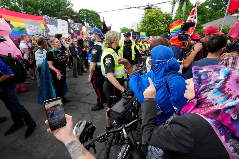 Counter-protesters and demonstrators square off against each other at a protest. Police are seen in the middle.