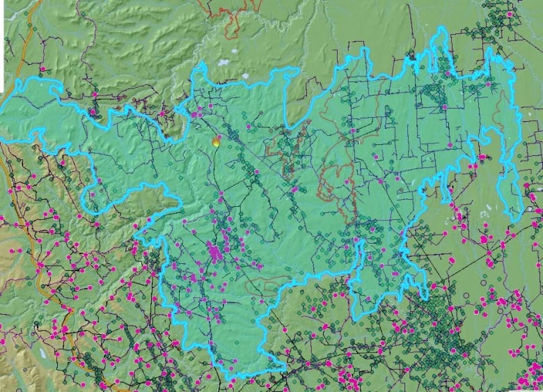 A map shows a large blue outline,  which is the perimeter of the Donnie Creek fire. Inside the blue outline, there are numerous coloured symbols that represent oil and gas wells, pipelines, and other energy infrastructure. 