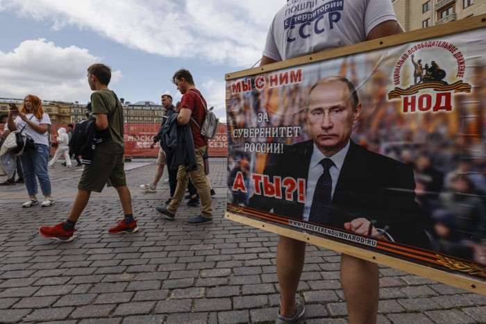 A member of the National Liberation Movement holds a poster in support of Russian president Vladimir Putin in Manezhnaya Square, outside the Kremlin