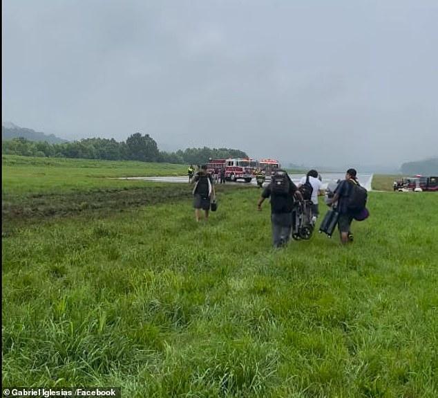 Those onboard can be seen holding their luggage as they cross the field back towards the fire crews