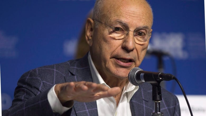 A man speaks into a microphone during a press conference.