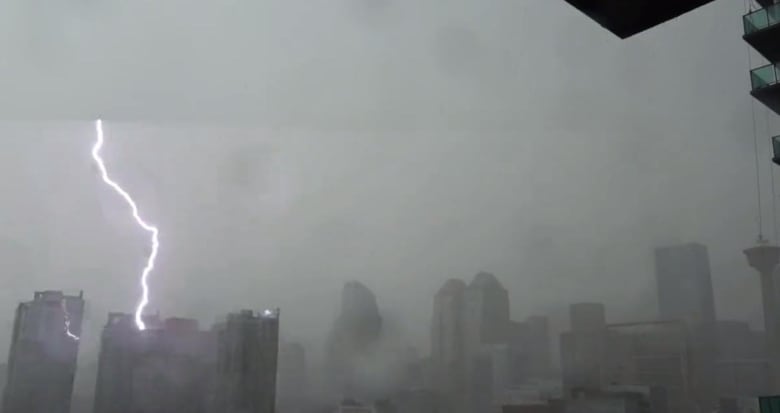 A lightning bolt appears to hit a tower in a downtown skyline. There are several tall buildings around it. 