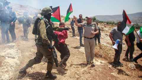 An Israeli soldier suppresses Palestinian protesters, during the demonstration