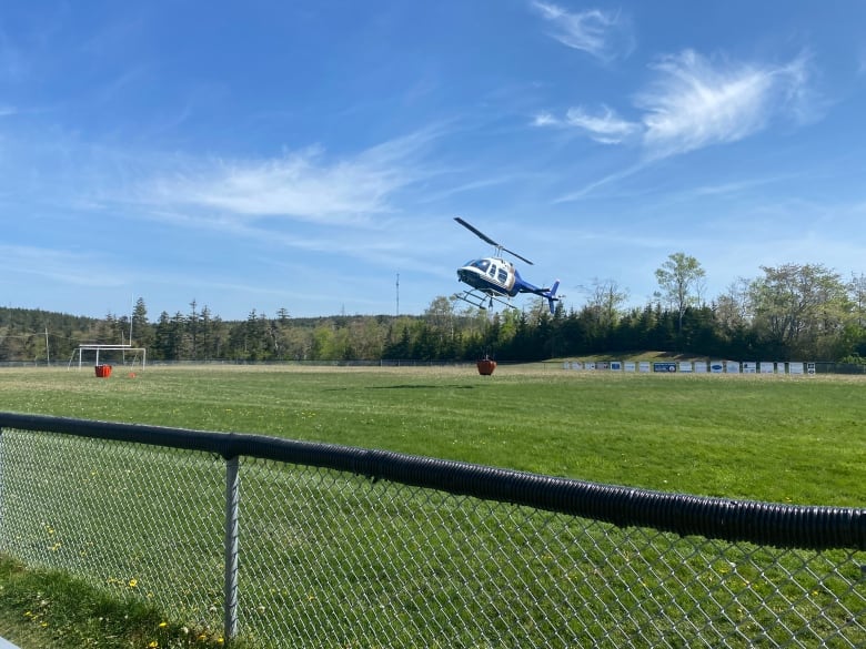 A helicopter is seen taking off from a soccer field.