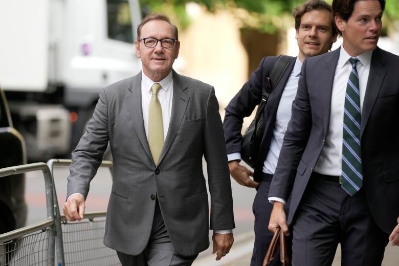 Three men walk along a street.