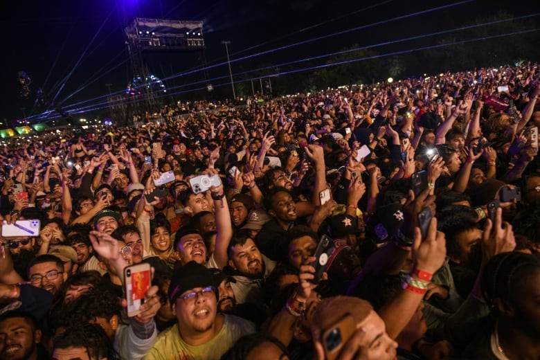 A crowd of people at an outdoor concert at night. 