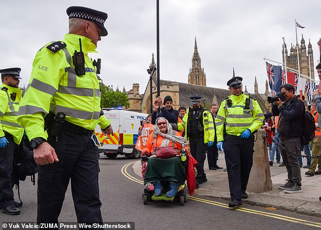 The friendly arm of the law: Police help Just Stop Oil protester in wheelchair into taxi