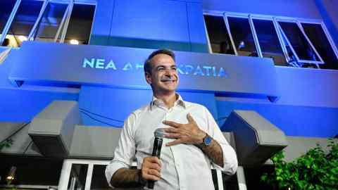 Kyriakos Mitsotakis in white open necked shirt talks to supporters at an election evening event