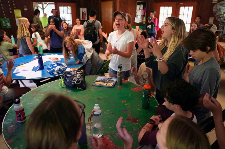 A room full of kids doing crafts indoors and singing