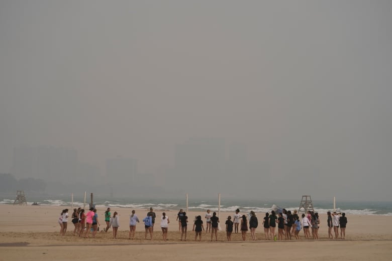 Teenagers play on a beach that is completely in a haze from smoke