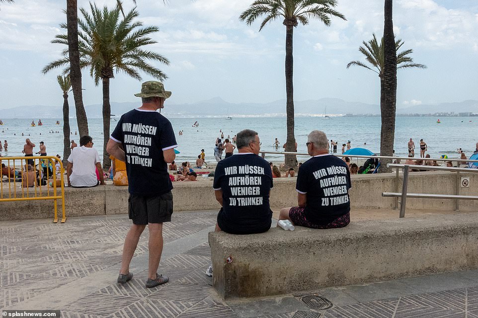 Three German gentlemen wear shirts saying: 'We need to stop drinking less' - the title of a Mallorca club hit