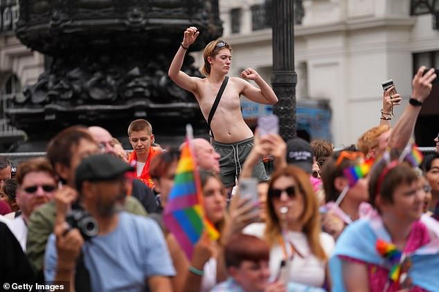 Crowds of people proudly hold rainbow flags as the march winds through the capital city