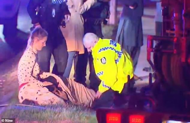 In an unusual scene, a female passerby stopped to comfort the injured passenger, while paramedics treated him, as he lay 'in agony' on the grass beside the wreck