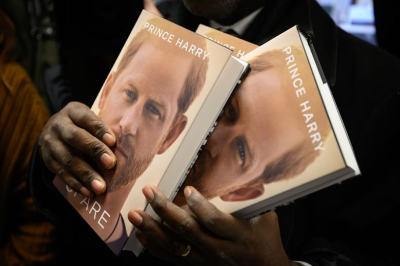 A person holds copies of a book in their hands.