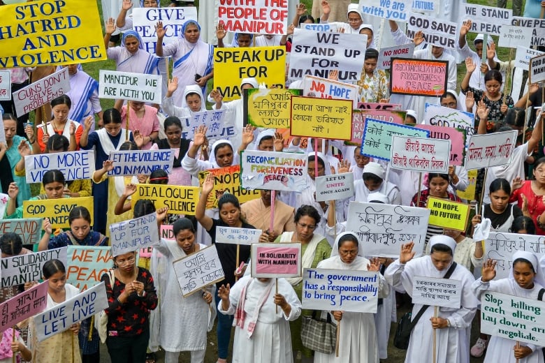 Dozens of people holding placards and signs condemning the violence in Manipur.