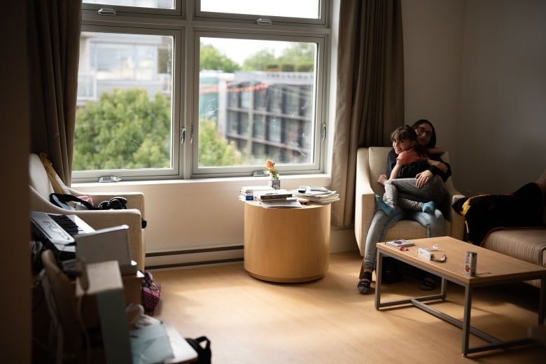 A mother and daughter snuggle on a chair at a recovery centre for women run by the Union Gospel Mission.