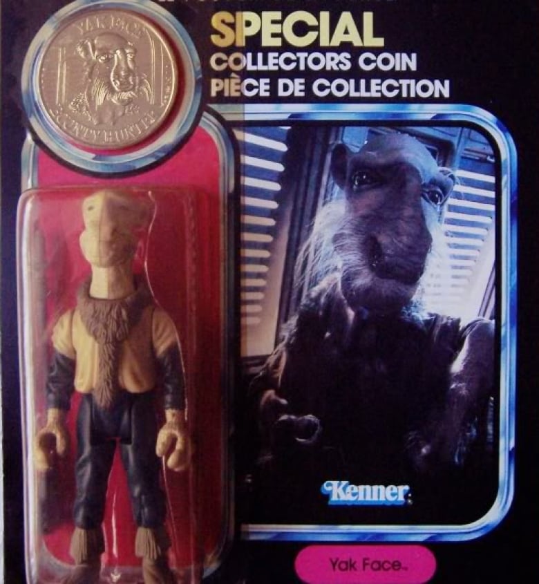 An alien figurine stands in its clear plastic packaging with a coloured backdrop. There is a coin above his head. The packaging says "Star Wars, The Power of the Force, Special Collectors Coin" in English and French. The logo for Kenner is near the bottom, as well as the character's name: "Yak Face"