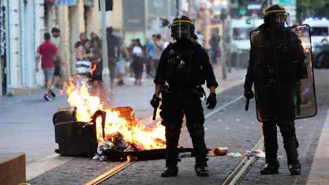 Riot police stand next to a burning bin in Marseille. Fear of public disorder and the reality of terrorist threats have pressured successive governments to expand the police arsenal, increase the number of officers and weaken their accountability