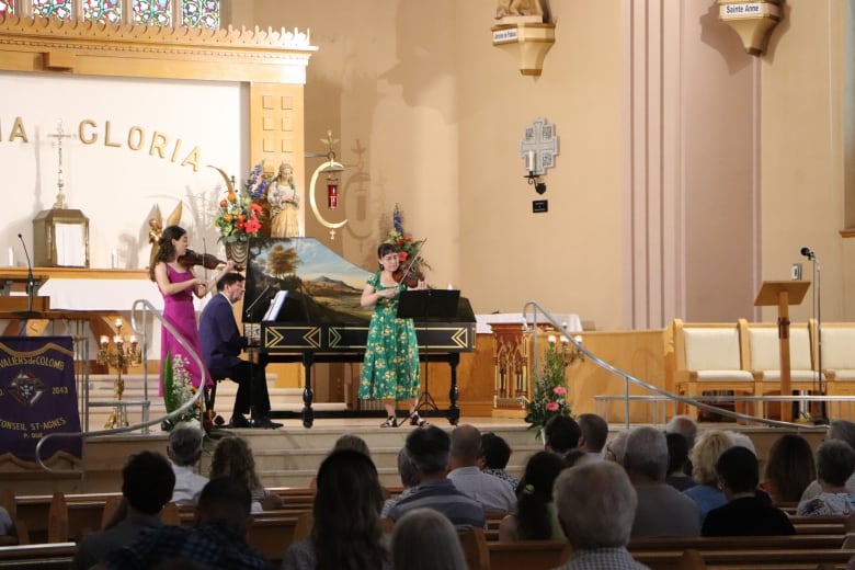 Three people play instruments in a church. 