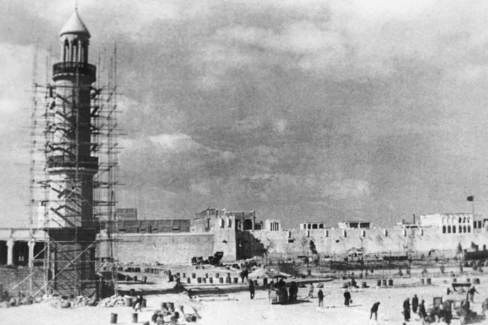 Scaffolding surrounds an old stone tower in a Middle Eastern coastal area