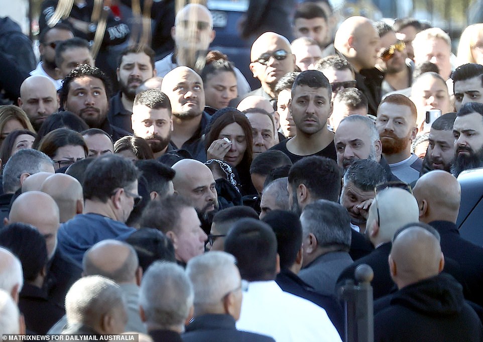 Men and women dabbed tears away from their eyes as hundreds swarmed the casket as it was lowered into the back of the hearse