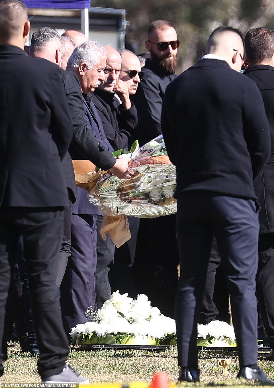 Men dressed in black carried flowers to lay at Mr Brikha's grave