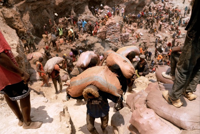 Artisanal miners carry sacks of ore at the Shabara mine near Kolwezi